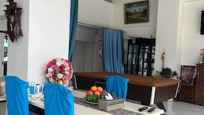 A dining area with a marble floor, a table set with chairs covered in blue fabric, a vase of flowers, and a fruit basket. - Alisara Apartments (Bangkok)