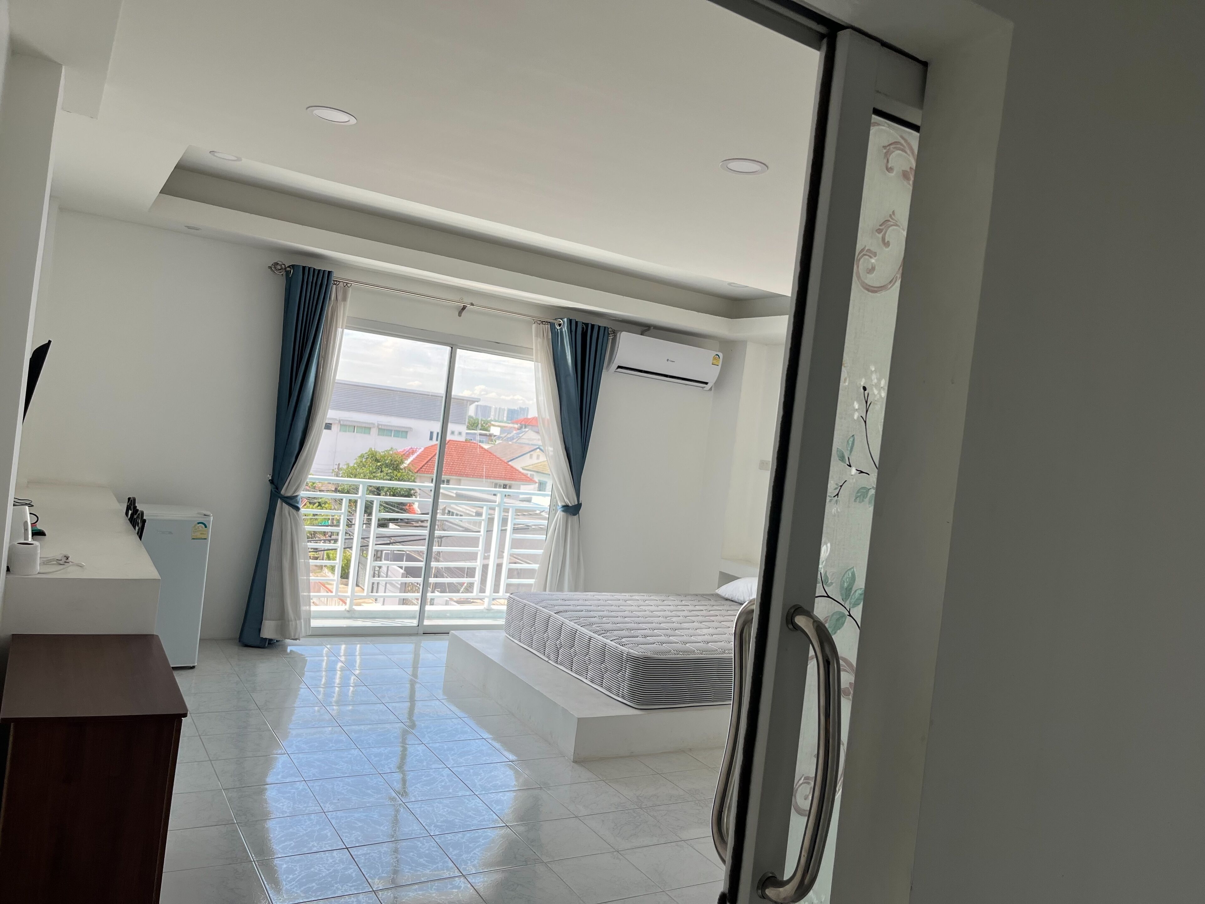 A modern hotel room with a balcony, a bed, a desk, and a wardrobe.
