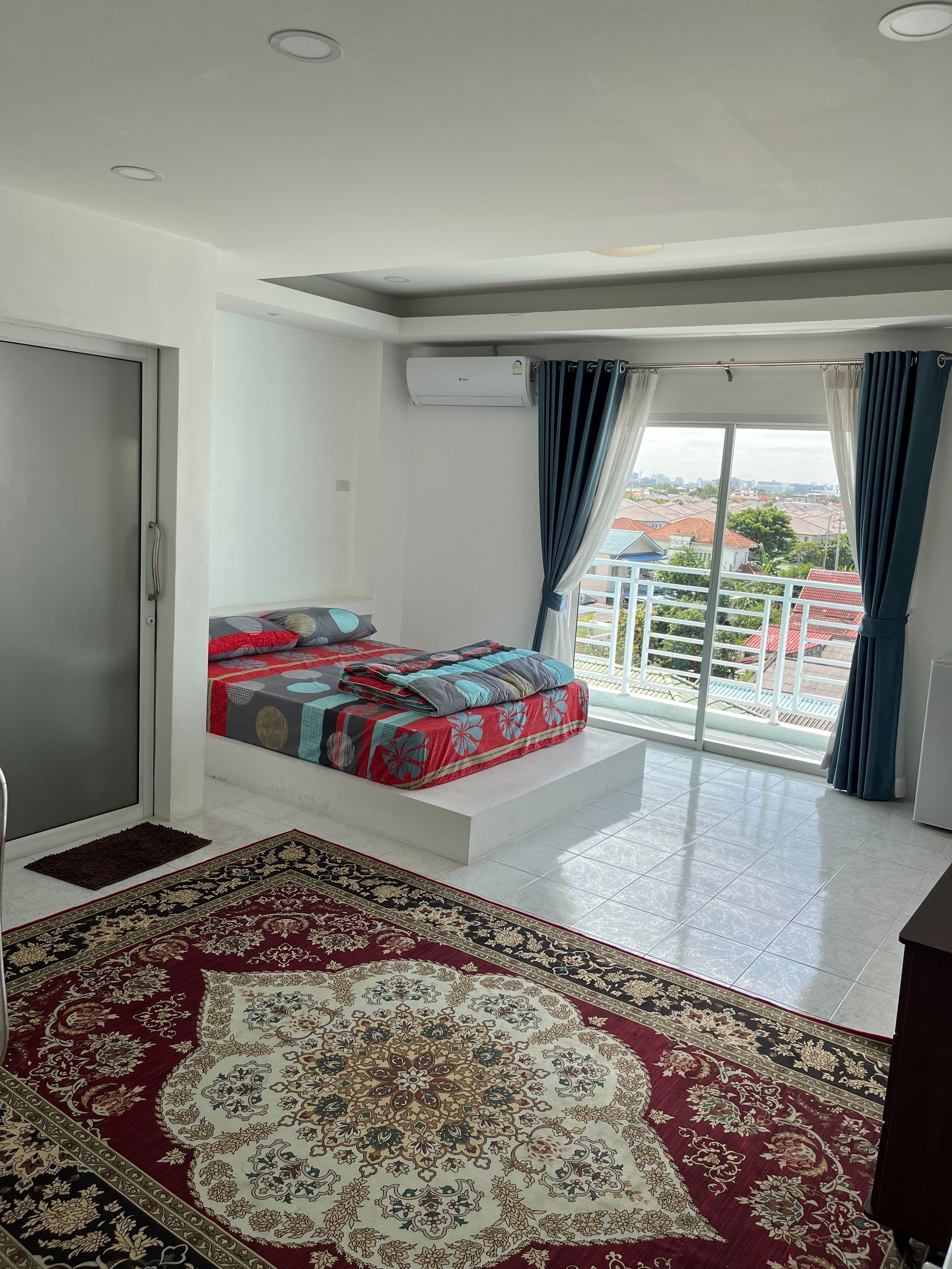 A bedroom with a bed, a large window, and a view of the city.