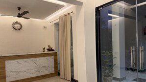 Ein Empfangsbereich mit Marmorladentheke, Deckenventilator und Glastür zu einem Balkon mit Topfpflanzen.