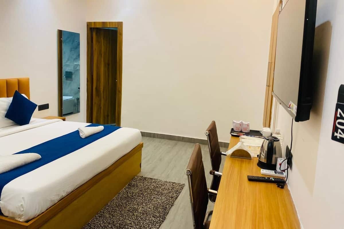 Une chambre d’hôtel équipée d’un lit, d’un bureau, d’une chaise, d’une télévision et d’un petit coin cuisine.