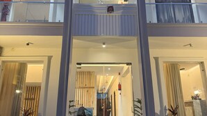 Ein zweistöckiges Gebäude mit einem mittleren Eingang, großen Fenstern und einem Balkon.