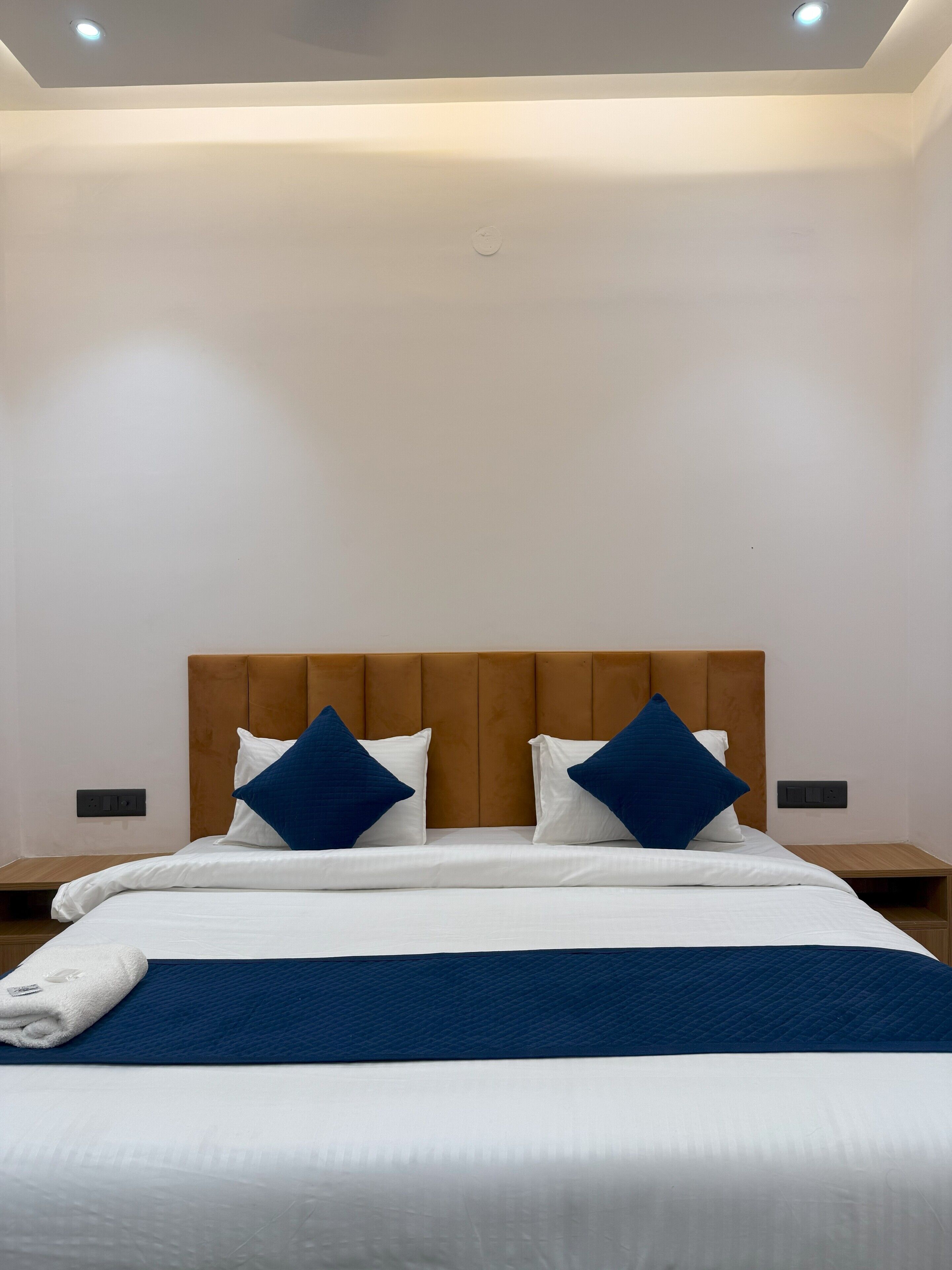 A modern hotel room with a large bed, a wooden headboard, and two nightstands.