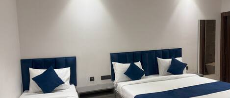 A hotel room with two beds, each with a headboard, a bedside table, and a mirror.
