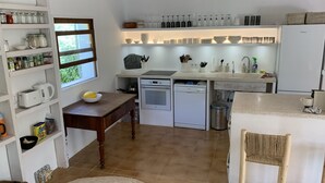 A compact kitchen with white cabinetry, a built-in oven, and a small island with a sink. - Son Floriany - House with private pool and lounge (Son Severa)