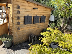 Una cabana de fusta amb zona de seients penjada a la paret, plantes en testos i una làmpada.
