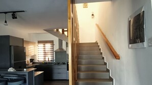 A modern kitchen with a central island, a staircase with wooden handrails, and a dining area with bar stools. - Lux Villa in Island of Mauritius, Grand Baie hidden Gem with poolside Bliss (Grand Baie)