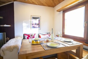 A dining table set with plates, glasses, and a bottle, in a room with wooden beams and a window.