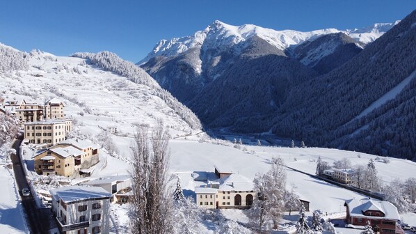 A snow-covered mountain village with traditional buildings, a clear sky, and a valley.