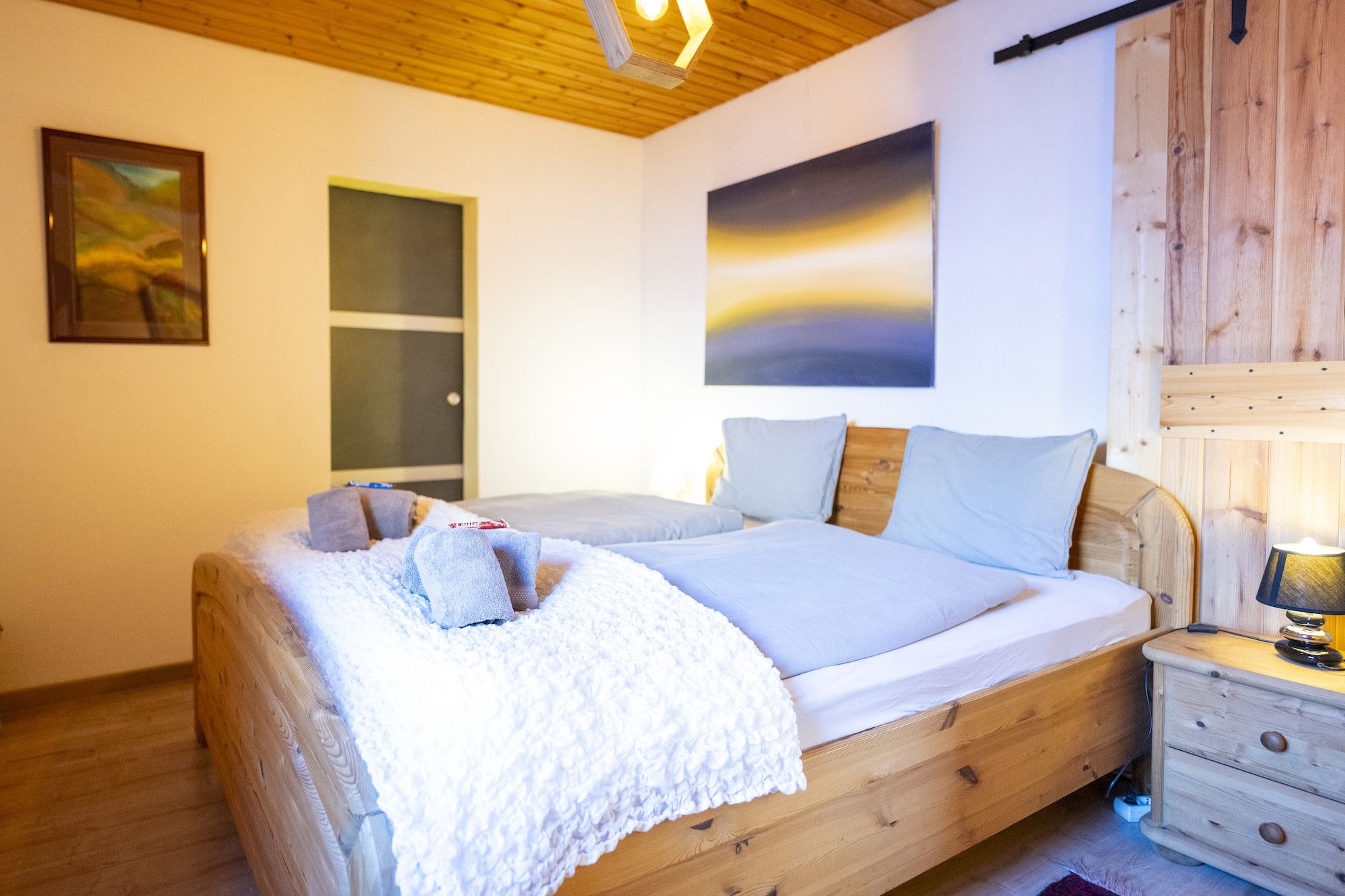 Un dormitorio con cama de madera, una mesita de noche, una lámpara y una puerta.