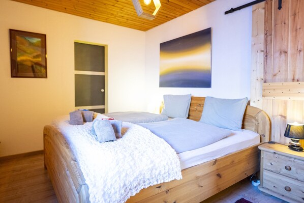 Un dormitorio con cama de madera, una mesita de noche, una lámpara y una puerta.
