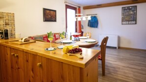 Una isla de cocina de madera con tabla de cortar, una botella y un cuenco de uvas.