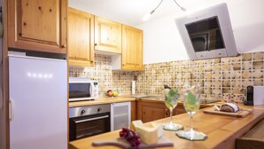 Una cocina moderna con armarios de madera, microondas, horno y una encimera con una copa de vino y queso.
