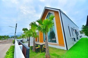 Ein modernes, zweistöckiges Haus mit Satteldach, großen Fenstern und einem gepflegten Rasen.
