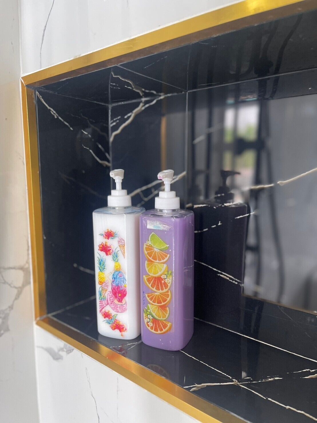 Two toiletry bottles on a black marble shelf.