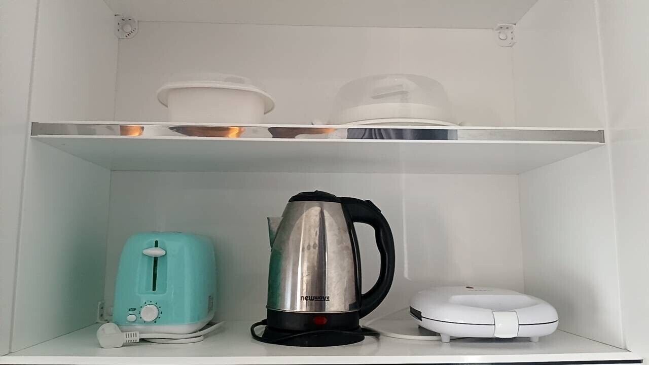 A kitchen with a toaster, kettle, and a white appliance on the countertop.