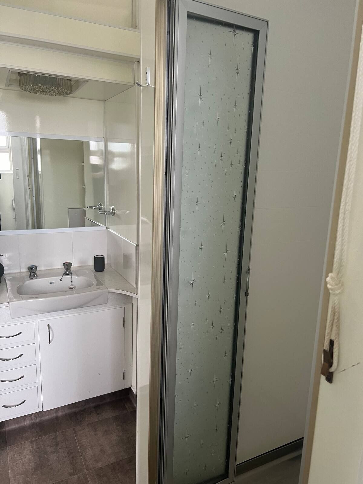 A bathroom with a white sink, mirror, and cabinets.