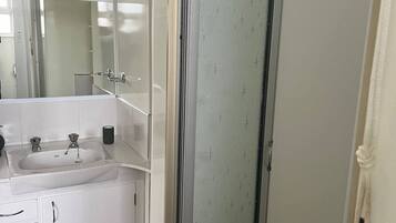 Un bagno con lavandino, specchio e mobili bianchi.
