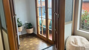 A room with a wooden door leading to a balcony, a small table with a plant, and a bean bag chair. - Heart of Windsor (Invercargill)