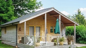 A wooden cabin with a porch, outdoor seating, and potted plants. - 2 bedroom accommodation in Oswestry (Oswestry)