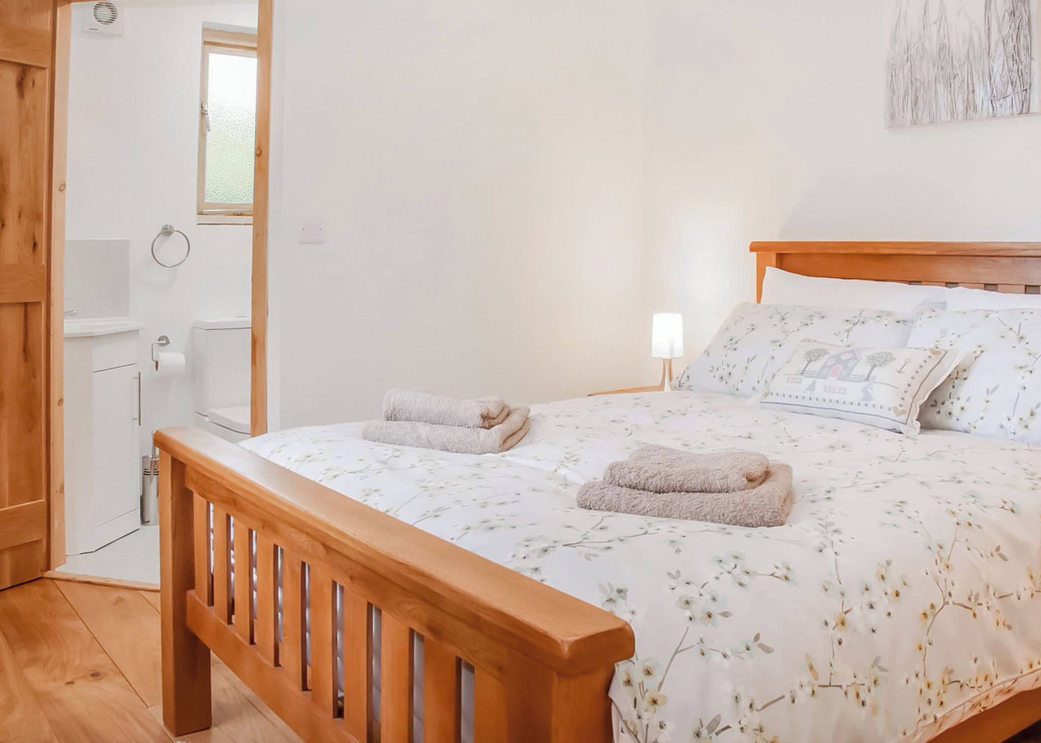 Een slaapkamer met een houten bed, een bedlampje en een raam.