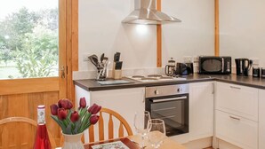A modern kitchen with white cabinets, a stainless steel range hood, a microwave, a toaster, and a coffee maker. - 2 bedroom accommodation in Oswestry (Oswestry)