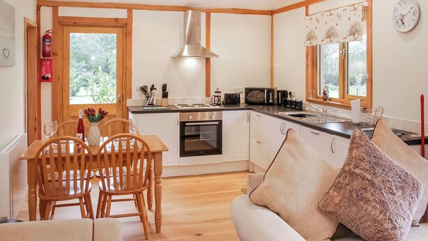 A compact kitchen with a microwave, oven, and wooden cabinets. - 2 bedroom accommodation in Oswestry (Oswestry)