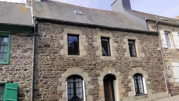 Un bâtiment en pierre doté de trois fenêtres en arc et d’une porte centrale.
