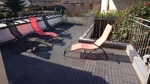 Une terrasse sur le toit, équipée de quatre chaises longues, d’une petite table et d’une rambarde.