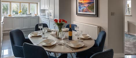 Comedor con una mesa redonda dispuesta para seis personas, rodeada de sillas tapizadas en azul.