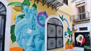 Un edificio con un mural colorido, una verja negra y un balcón.