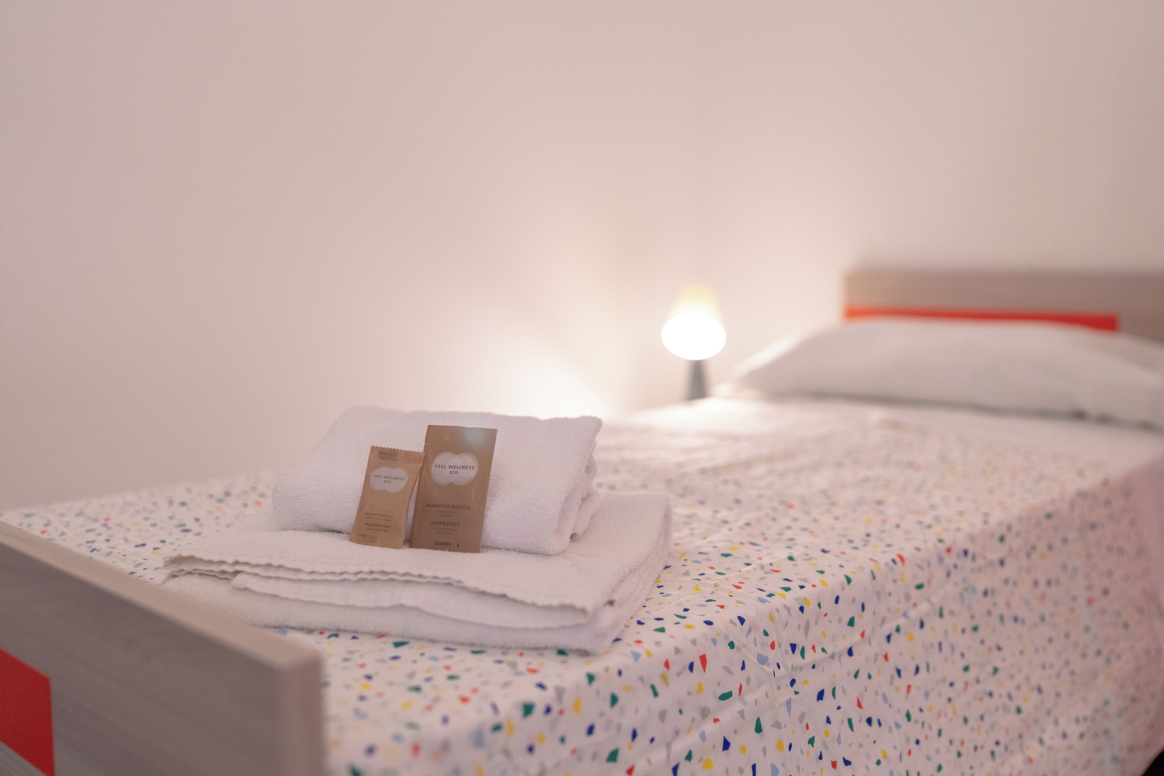 Ein ordentlich bezogenes Bett mit gefalteten weißen Handtüchern und einer Shampoo-Flasche.