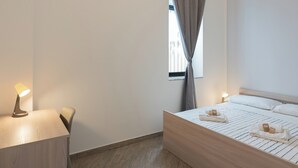 Un dormitorio moderno con una cama de madera, mesitas de noche y lámparas colgantes.