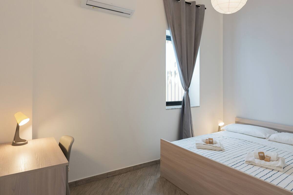 Un dormitorio moderno con una cama de madera, mesitas de noche y lámparas colgantes.