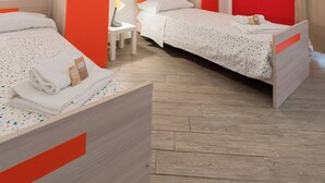 Habitación de hotel con dos camas individuales, una mesita con lámpara y un adorno en la pared.
