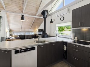 A modern kitchen with a dishwasher, a sink, and a window overlooking greenery.