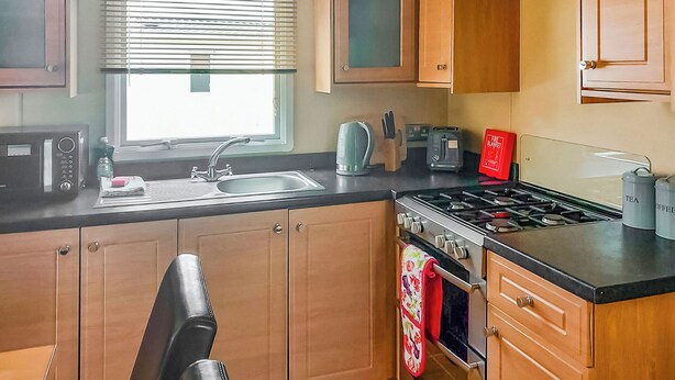 Une cuisine de taille réduite, équipée d’un évier, d’une cuisinière et de divers appareils électroménagers.