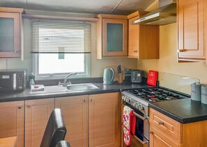 A compact kitchen with a sink, stove, and various appliances.