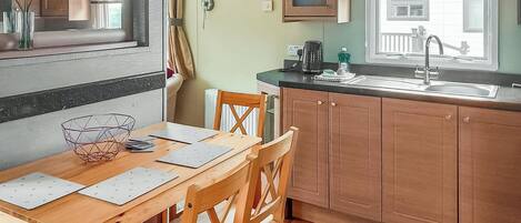 A kitchen with wooden cabinets, a dining table with chairs, a window with blinds, and a radiator.