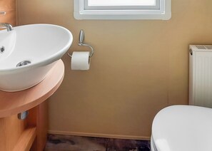 A bathroom with a white sink, toilet, and a towel rack. - 1 bedroom accommodation in Langworth (Langworth)