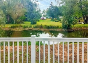 A serene lakeside view with a white fence in the foreground, a grassy area, and a small building in the distance. - 2 bedroom accommodation in Langworth (Langworth)
