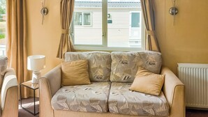 A living room with a sofa, a lamp, and a view of a house through a window.