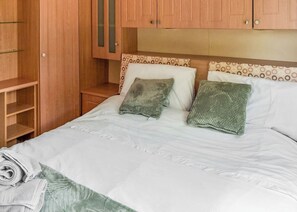 A hotel room with a bed, a wardrobe, and a small bedside table.