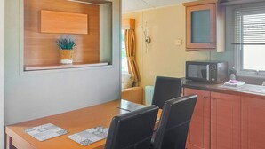 Une cuisine de taille réduite comprenant une table à manger, des chaises, un four à micro-ondes et une fenêtre avec des stores.