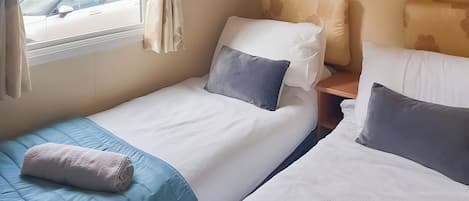 Une chambre d’hôtel avec deux lits simples, une fenêtre avec des rideaux, une table de chevet et une vue sur l’extérieur.