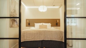 A modern bedroom with a large bed, a wooden headboard, and a hanging light fixture.