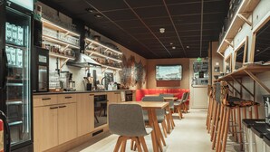 A modern restaurant with wooden furniture, a coffee machine, and shelves with glassware.