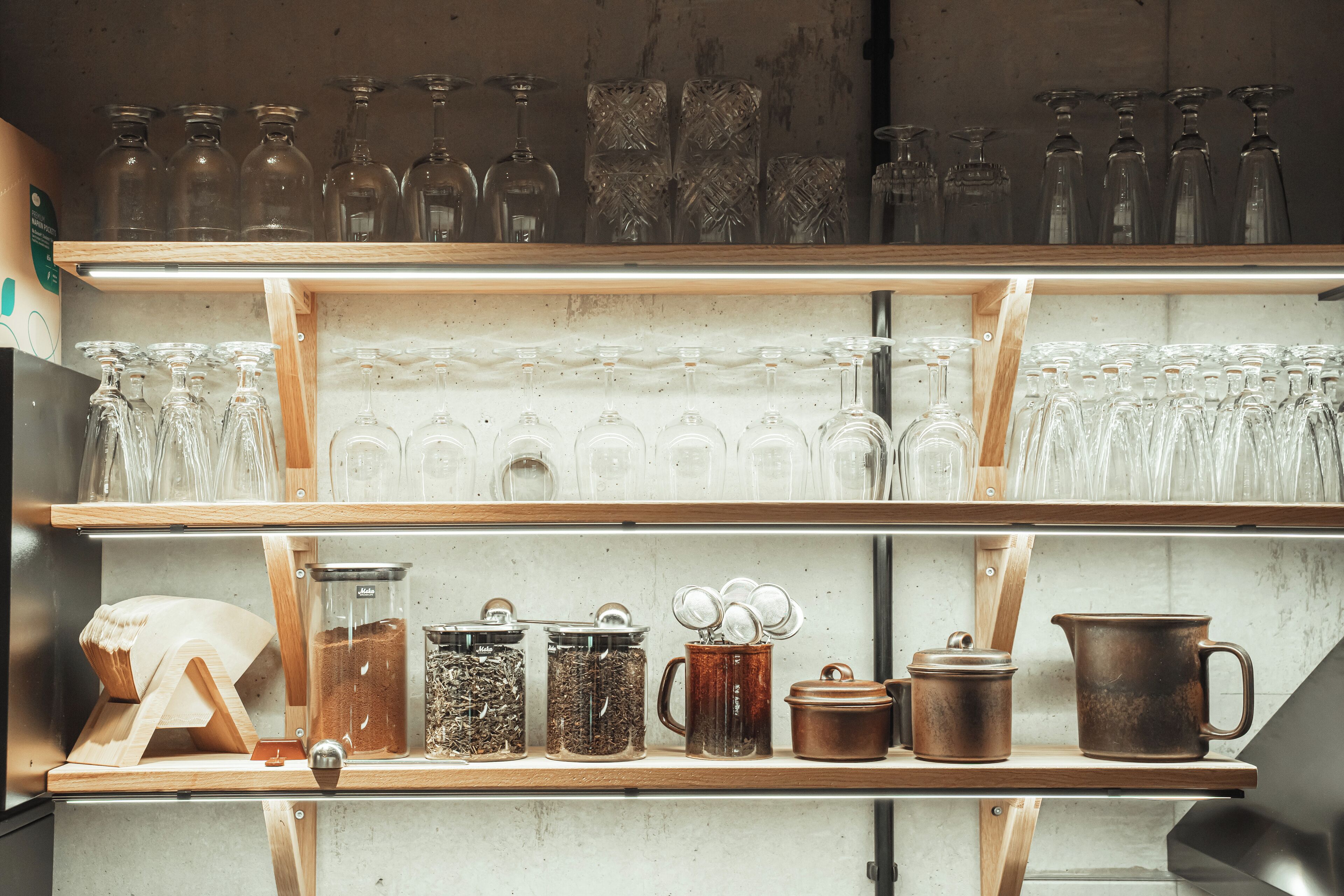 A kitchen shelf with various glassware, jars, and cooking utensils.