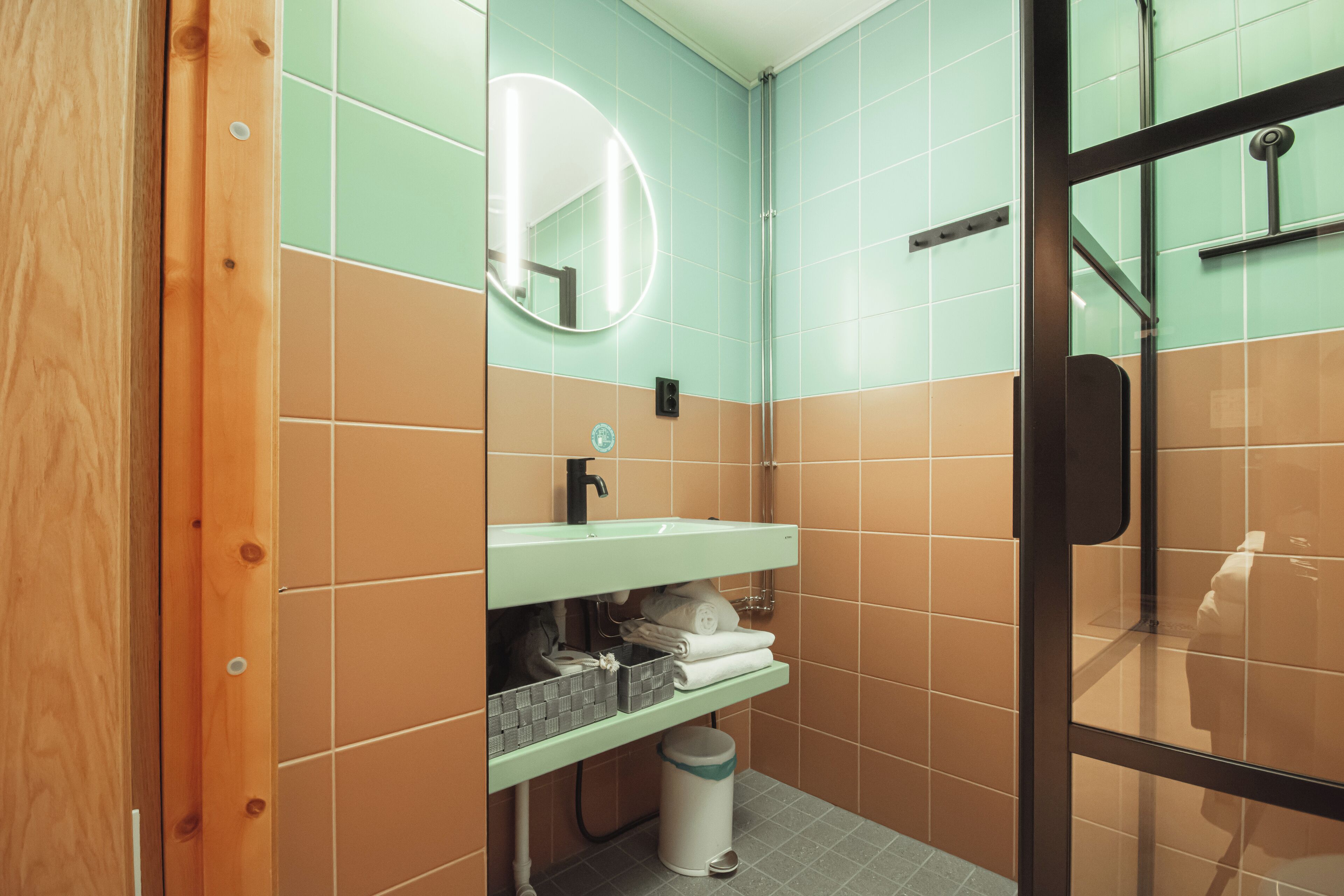 A bathroom with a wooden door, a green sink, and a mirror.