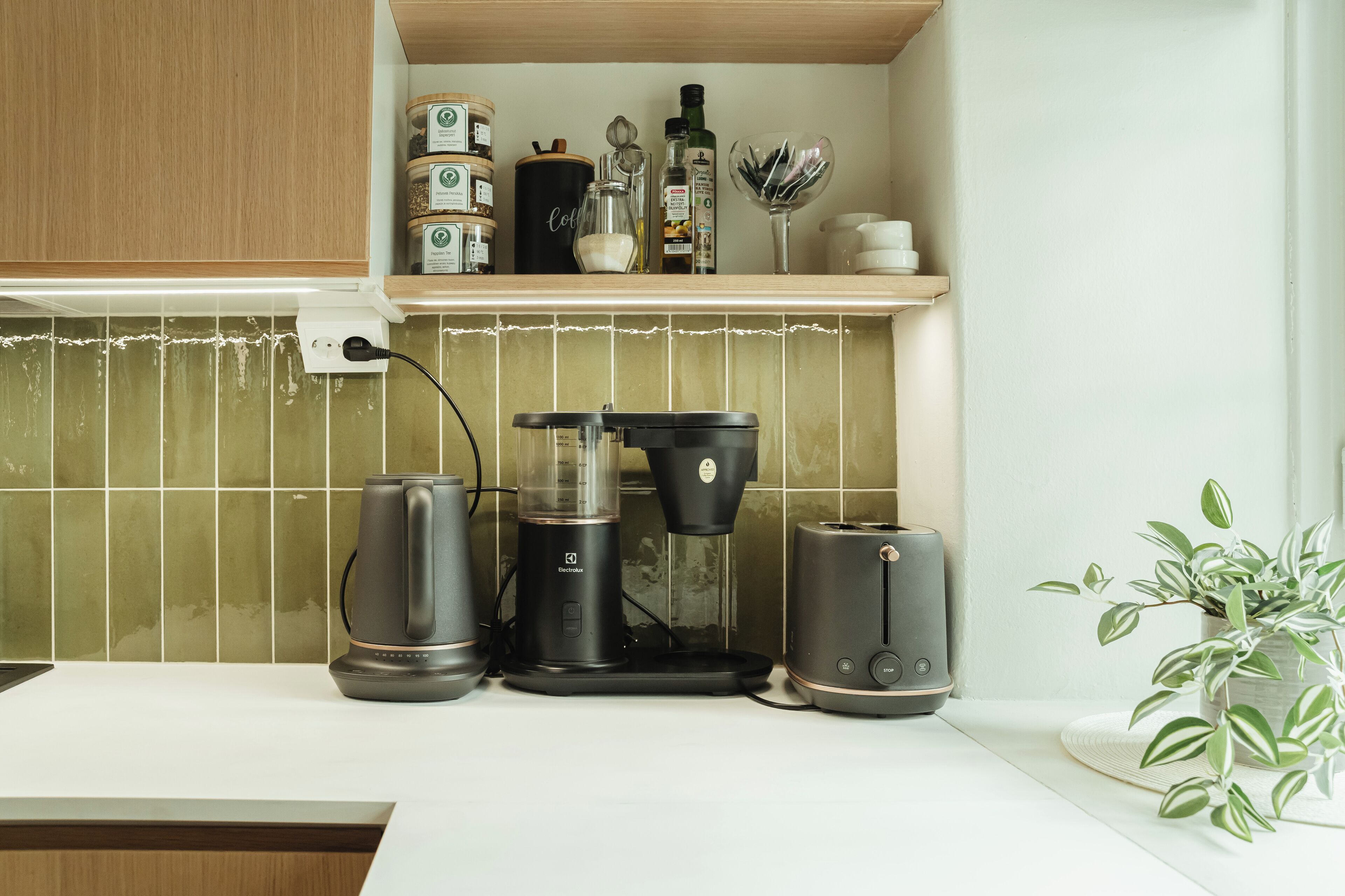 Une cuisine équipée d’une machine à café, d’un grille-pain et d’une bouilloire, le tout posé sur le plan de travail.
